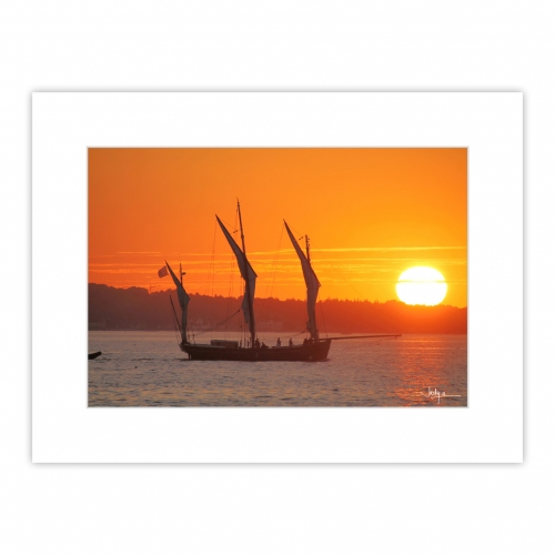 Coucher de soleil sur la Baie de Concarneau, le vieux gréement Le Corentin rentre au port et passe devant le soleil couchant