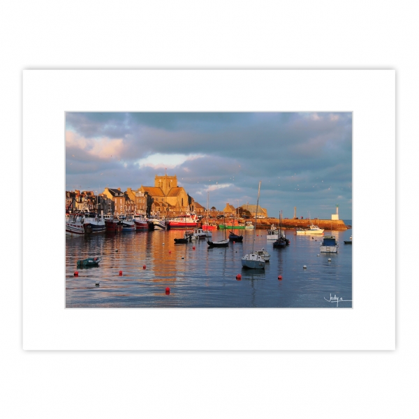 Coucher de soleil de janvier sur le Port de Barfleur, les façades et l'église aux teintes dorées se reflètent dans les eaux du port – Manche – Normandie